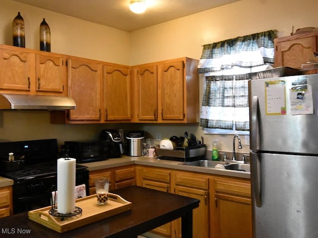 kitchen featuring brown cabinets, light countertops, a sink, under cabinet range hood, and black appliances