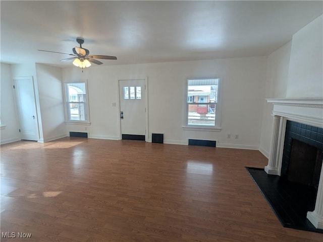 unfurnished living room with dark wood-type flooring, a fireplace, a ceiling fan, and baseboards