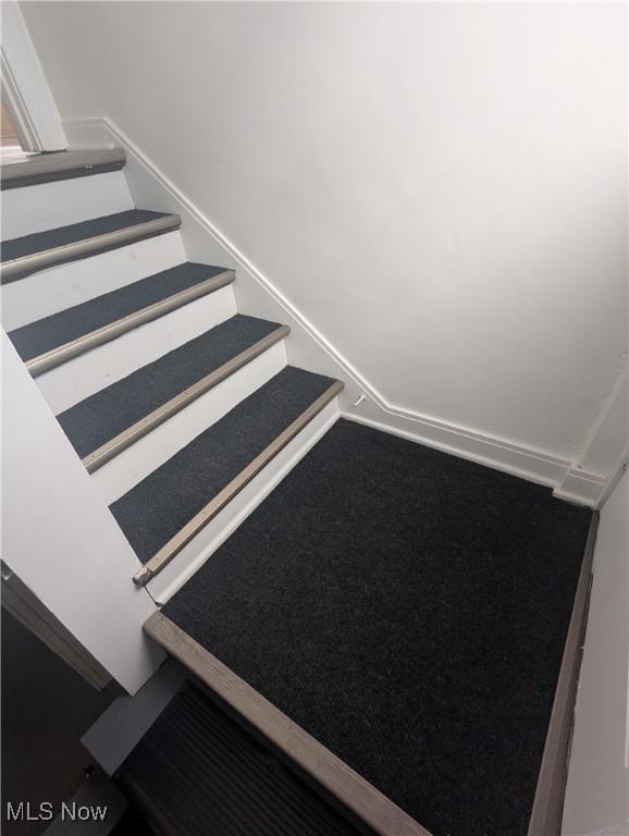 staircase featuring carpet and baseboards