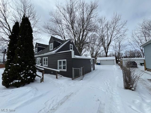 view of snow covered exterior with a garage and an outbuilding