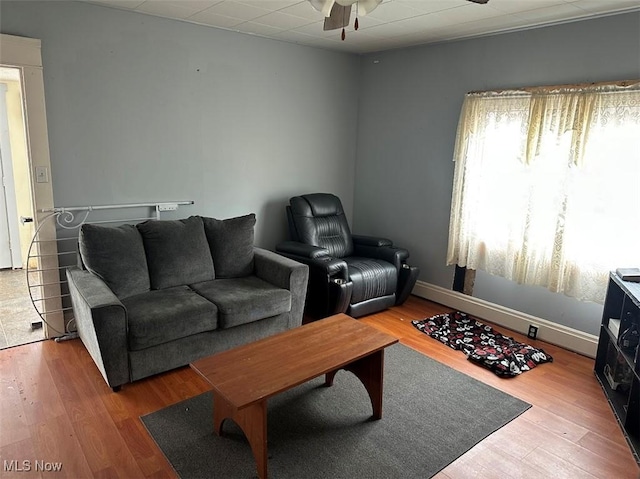 living area featuring ceiling fan, baseboards, and wood finished floors