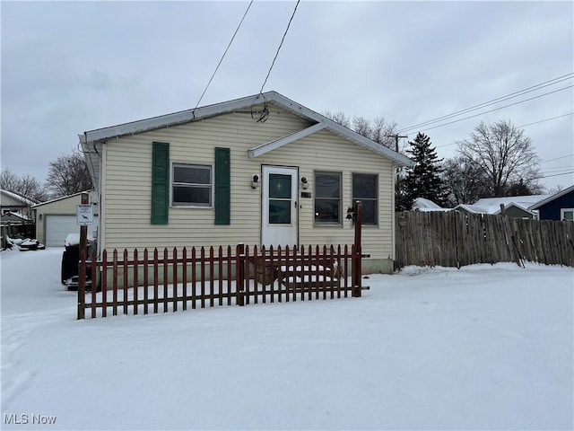 bungalow-style house featuring a garage, a fenced front yard, and an outbuilding