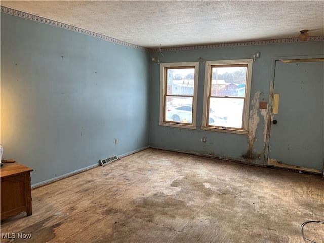 spare room featuring visible vents, a textured ceiling, and baseboards