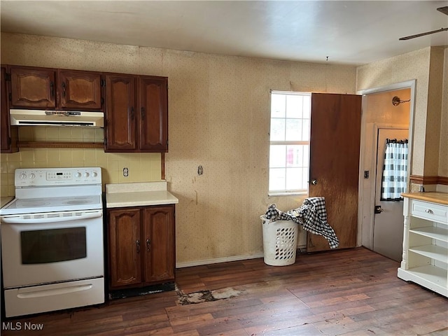 kitchen with under cabinet range hood, dark wood-type flooring, light countertops, and electric stove