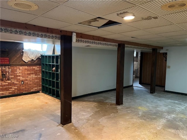 below grade area featuring brick wall, visible vents, and baseboards