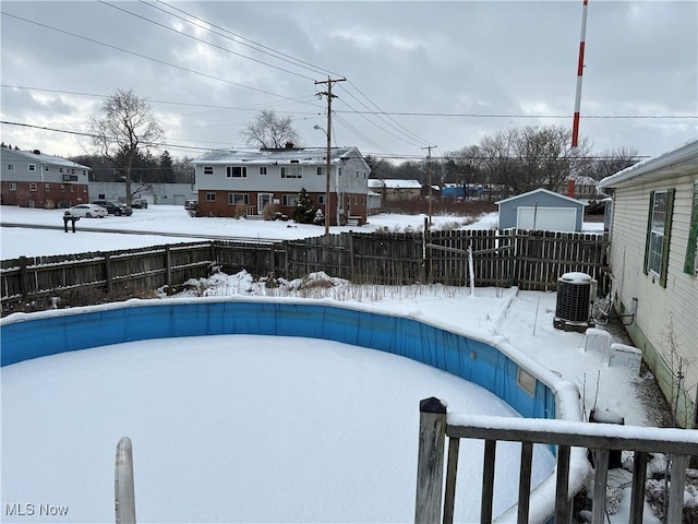 snow covered pool with fence, a pool, and cooling unit