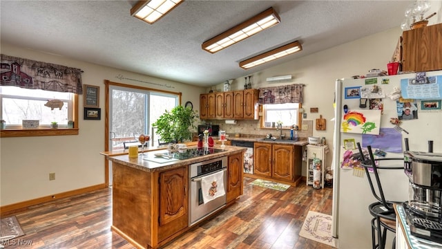 kitchen with brown cabinets, black electric stovetop, lofted ceiling, freestanding refrigerator, and stainless steel oven