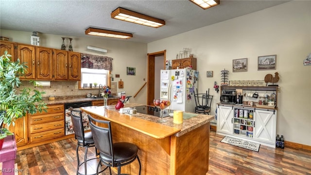 kitchen with brown cabinetry, dark wood-type flooring, a center island, light countertops, and white fridge with ice dispenser