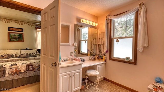 full bath with vanity, baseboards, and a textured ceiling