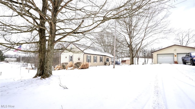 yard layered in snow with a garage and an outbuilding