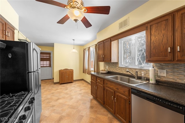 kitchen featuring stainless steel appliances, dark countertops, tasteful backsplash, visible vents, and a sink