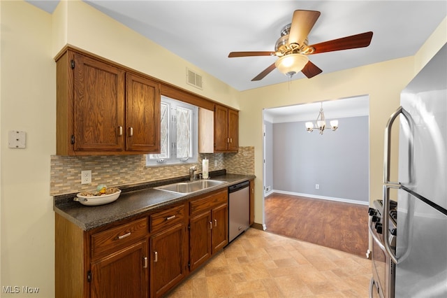 kitchen featuring stainless steel appliances, dark countertops, visible vents, brown cabinetry, and a sink