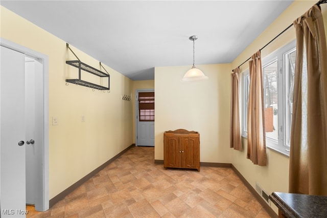 unfurnished dining area featuring stone finish flooring, visible vents, and baseboards