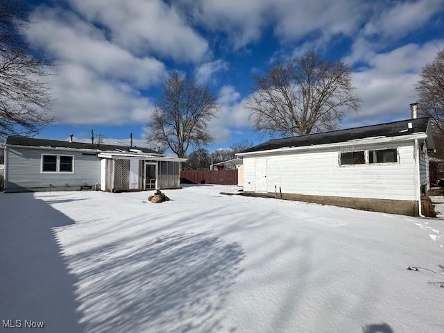 snow covered rear of property featuring fence