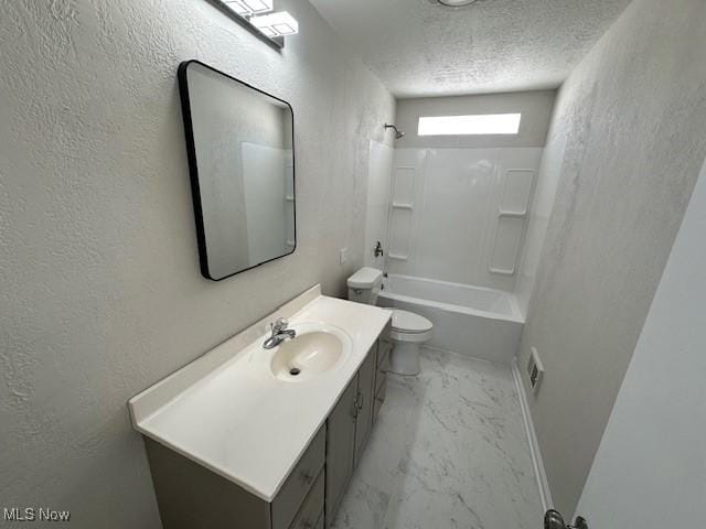 full bath with a textured ceiling, marble finish floor, a textured wall, and vanity