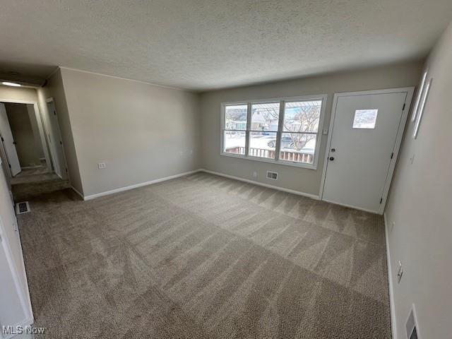 interior space featuring baseboards, visible vents, and a textured ceiling