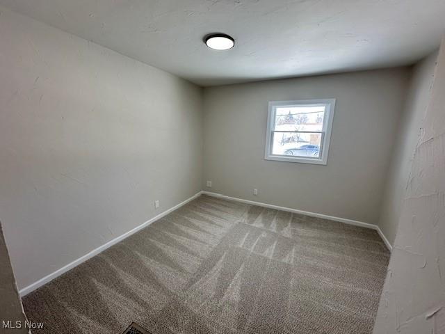 unfurnished room with carpet flooring and baseboards