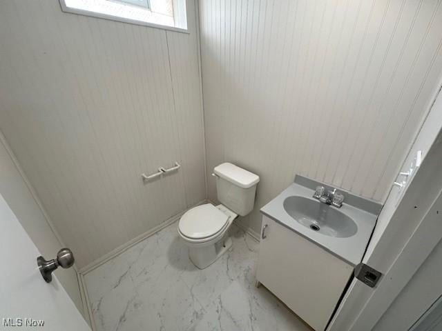 bathroom with marble finish floor, vanity, and toilet