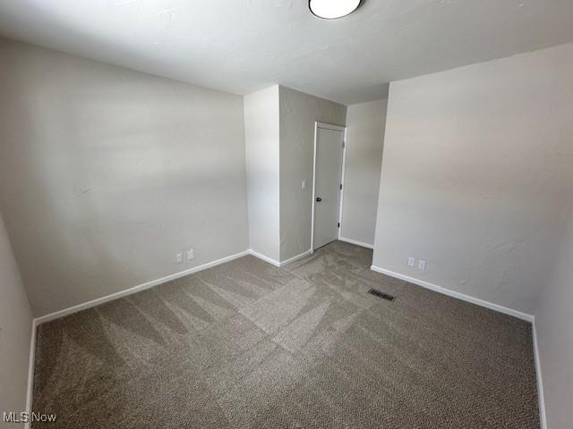 carpeted spare room featuring visible vents and baseboards