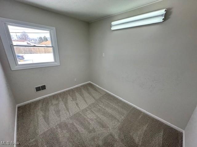 carpeted empty room with visible vents and baseboards