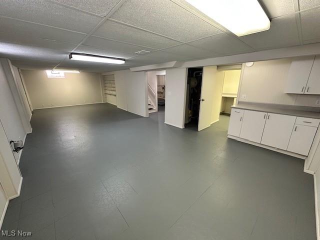 basement with a drop ceiling and stairs