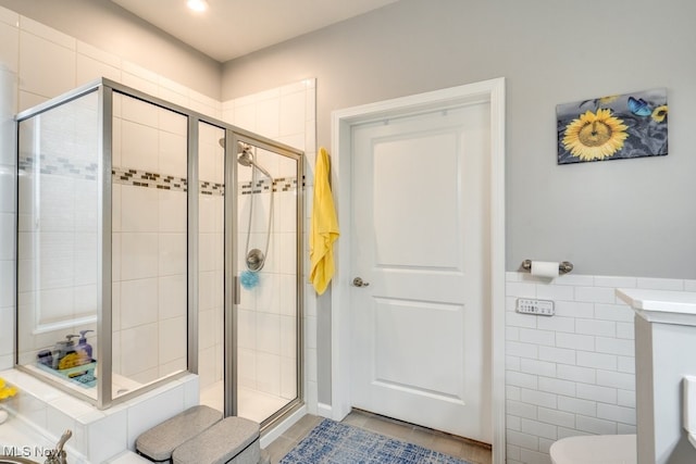 bathroom featuring a stall shower, wainscoting, tile walls, and tile patterned floors