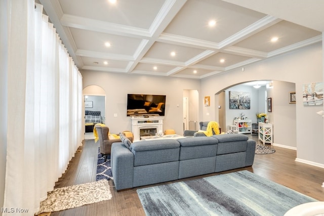 living room with arched walkways, dark wood-style flooring, coffered ceiling, beam ceiling, and a glass covered fireplace