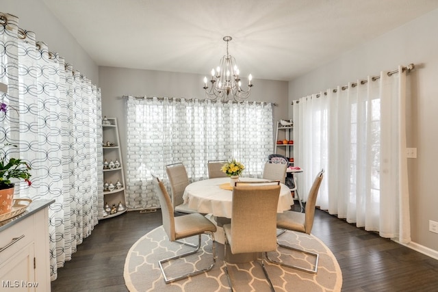 dining space featuring dark wood-type flooring and a notable chandelier