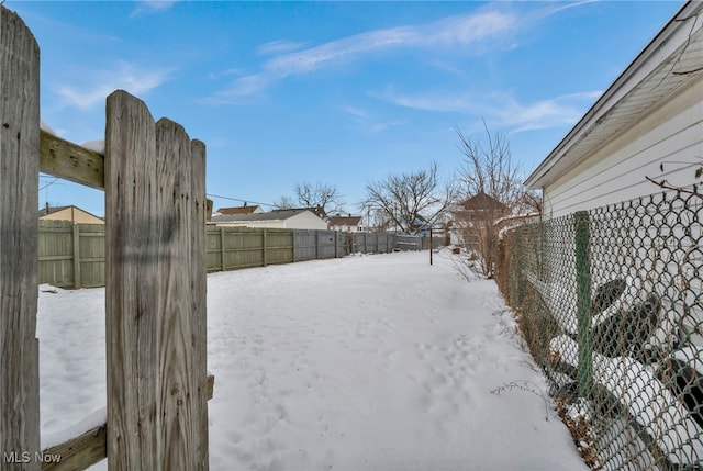 yard layered in snow featuring a fenced backyard