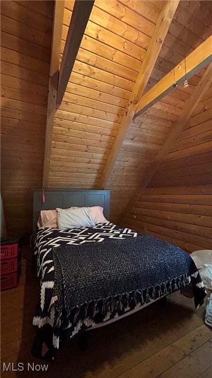 unfurnished bedroom featuring lofted ceiling with beams, wood walls, wood finished floors, and wood ceiling