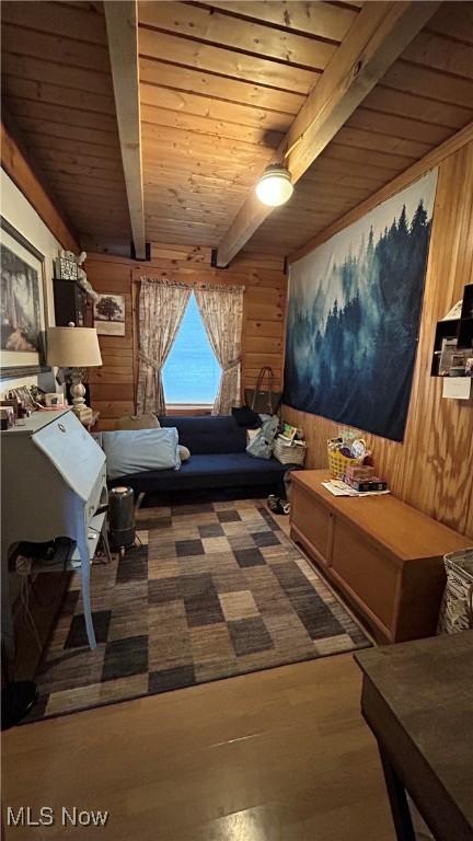 sitting room featuring beamed ceiling, wood walls, wooden ceiling, and wood finished floors