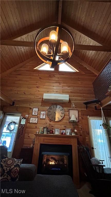 unfurnished living room featuring a wall unit AC, lofted ceiling with beams, a chandelier, and a glass covered fireplace