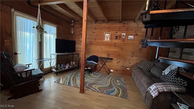 living area with light wood-style flooring, wooden ceiling, beam ceiling, and wooden walls