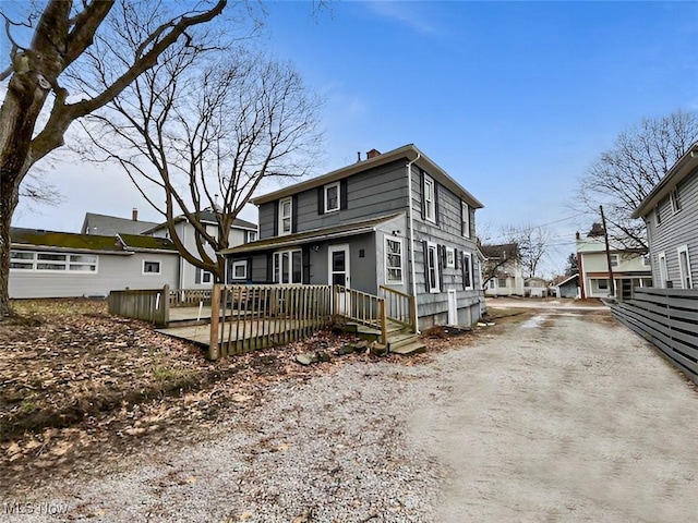 view of front of home featuring a chimney, driveway, and a deck