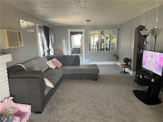 carpeted living room with a wall unit AC, baseboards, and a textured ceiling