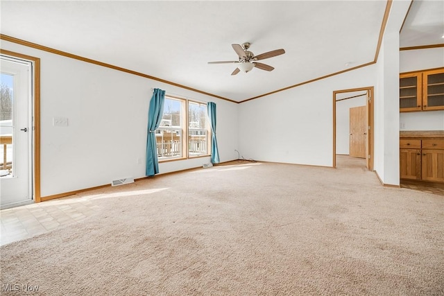unfurnished living room with ornamental molding, light colored carpet, visible vents, and a ceiling fan