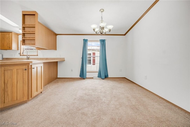 kitchen featuring decorative light fixtures, light countertops, an inviting chandelier, ornamental molding, and light carpet