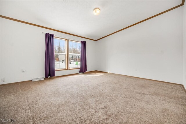 carpeted spare room with visible vents, crown molding, and baseboards
