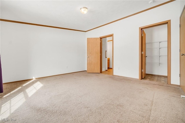 unfurnished bedroom with ornamental molding, light carpet, a spacious closet, and baseboards