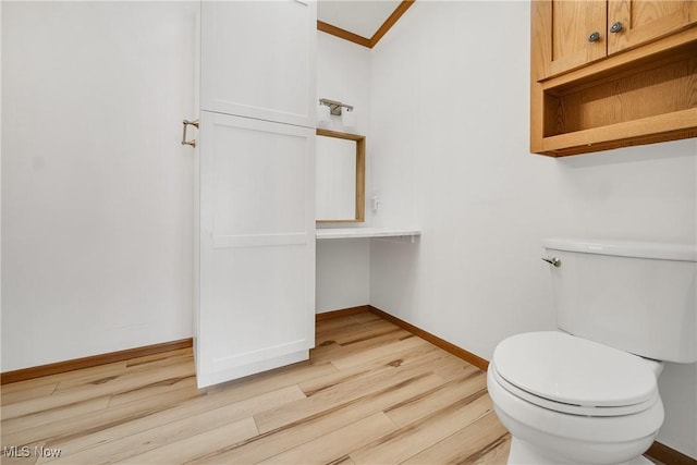 bathroom with ornamental molding, wood finished floors, toilet, and baseboards