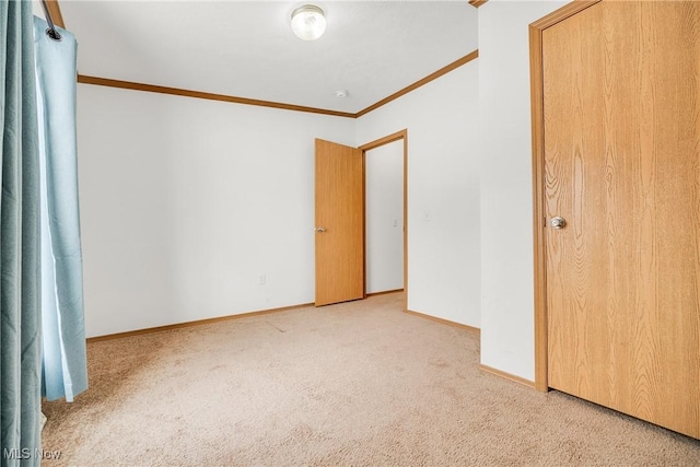 unfurnished bedroom featuring baseboards, ornamental molding, and light colored carpet