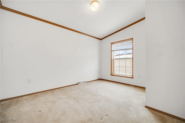 carpeted empty room featuring vaulted ceiling, ornamental molding, visible vents, and baseboards
