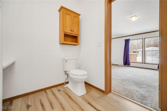 half bathroom featuring toilet, baseboards, and wood finished floors