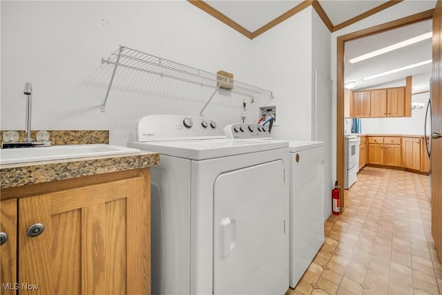 washroom with laundry area, ornamental molding, washer and clothes dryer, and a sink