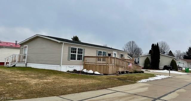 manufactured / mobile home featuring a front lawn and a wooden deck