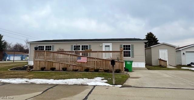 manufactured / mobile home featuring a front lawn, a deck, and an outdoor structure