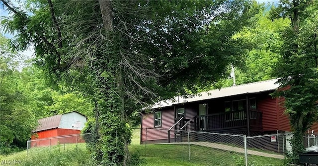 exterior space featuring fence private yard, faux log siding, and a front lawn