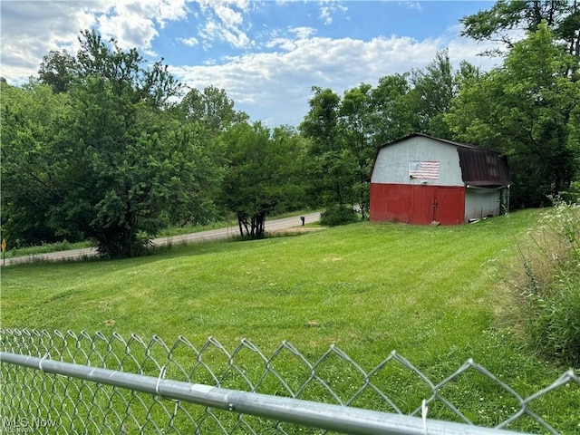 view of yard featuring a barn, fence, and an outbuilding