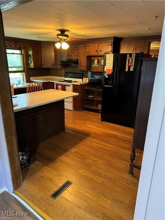 920 Caywood Rd, Marietta, OH 45750 - kitchen with under cabinet range hood, light countertops, black refrigerator with ice dispenser, light wood finished floors, and white range with electric cooktop