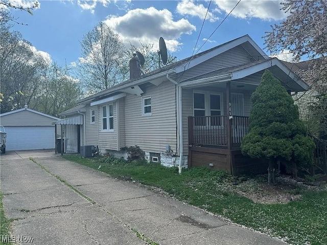 view of side of home featuring a chimney, a detached garage, central AC, and an outbuilding